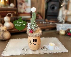 A unique Christmas elf decoration made with a dried gourd. The elf is named Fizzle and wearing a custom pointy hat. Battery candle included.